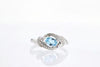 RINGS - 18K White Gold Oval Blue Topaz And Diamond Bypass Style Ring